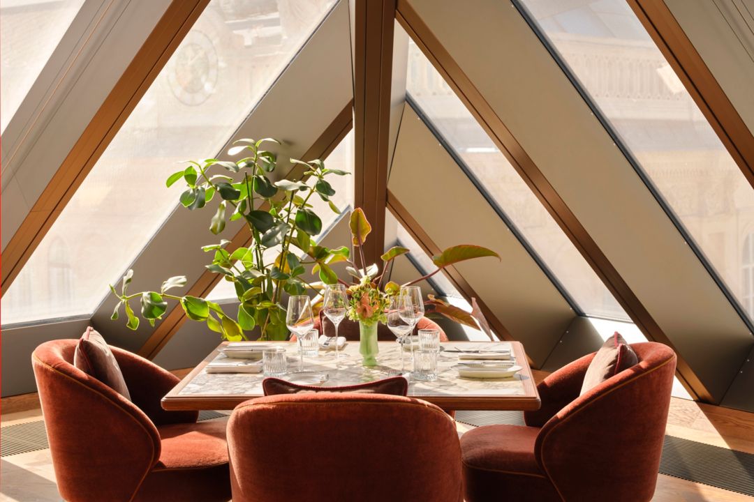 A dining table set with wine glasses, plates, and a flower arrangement, surrounded by chairs.